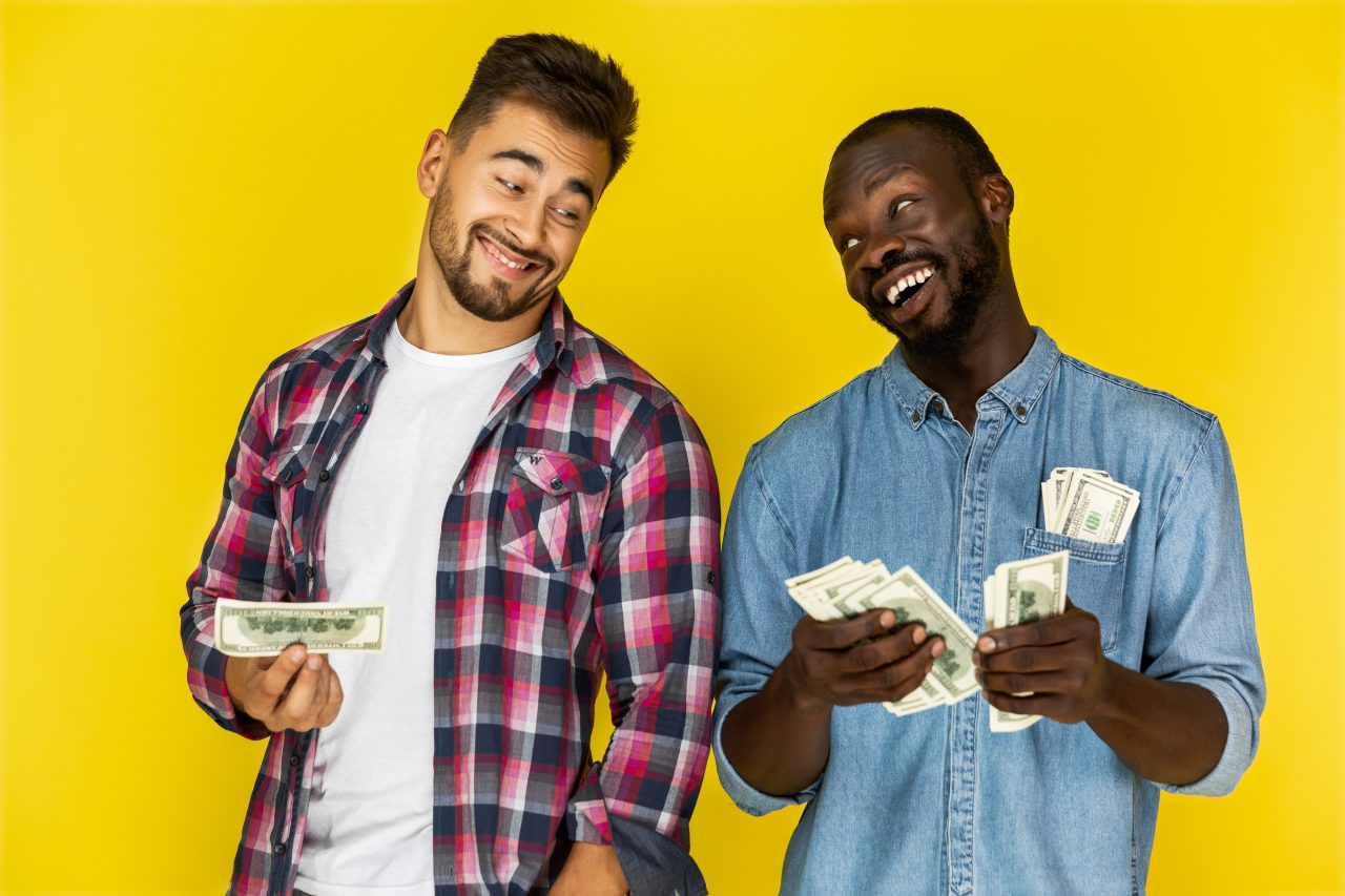 afroamerican-guy-is-sharing-money-with-european-guy-informal-clothes-both-are-hapily-laughing (1)
